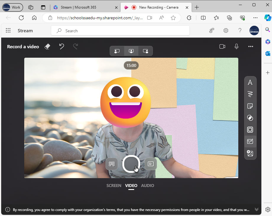 Video recording interface with 2 different backgrounds and the webcam visible. An emoji has been added to cover the person&rsquo;s face.