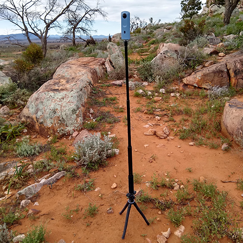 Setup for taking a 360 photo in an outdoor setting: the 360 camera is mounted to a selfie stick that&rsquo;s attached to a tripod. The transparent acrylic disk between camera and selfie stick isn&rsquo;t visible. It&rsquo;s an overcast day so there&rsquo;s no shadow.